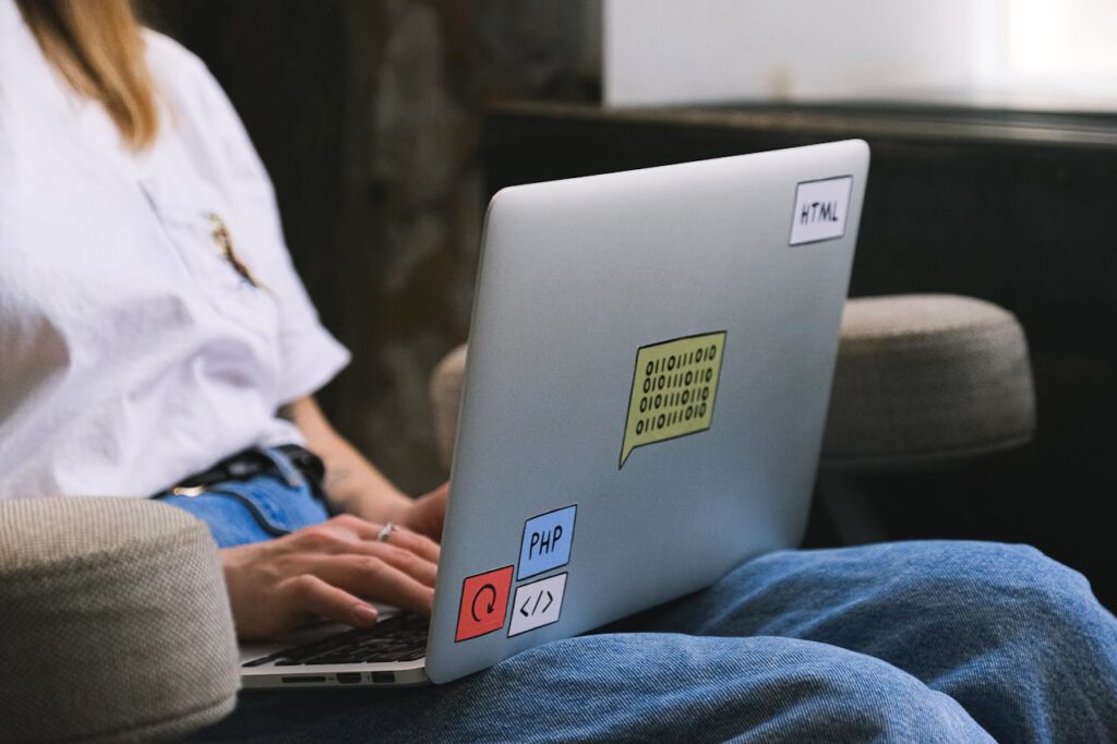 pexels-photo-12662875 Person typing on a laptop with coding stickers, symbolizing remote work and freelancing.