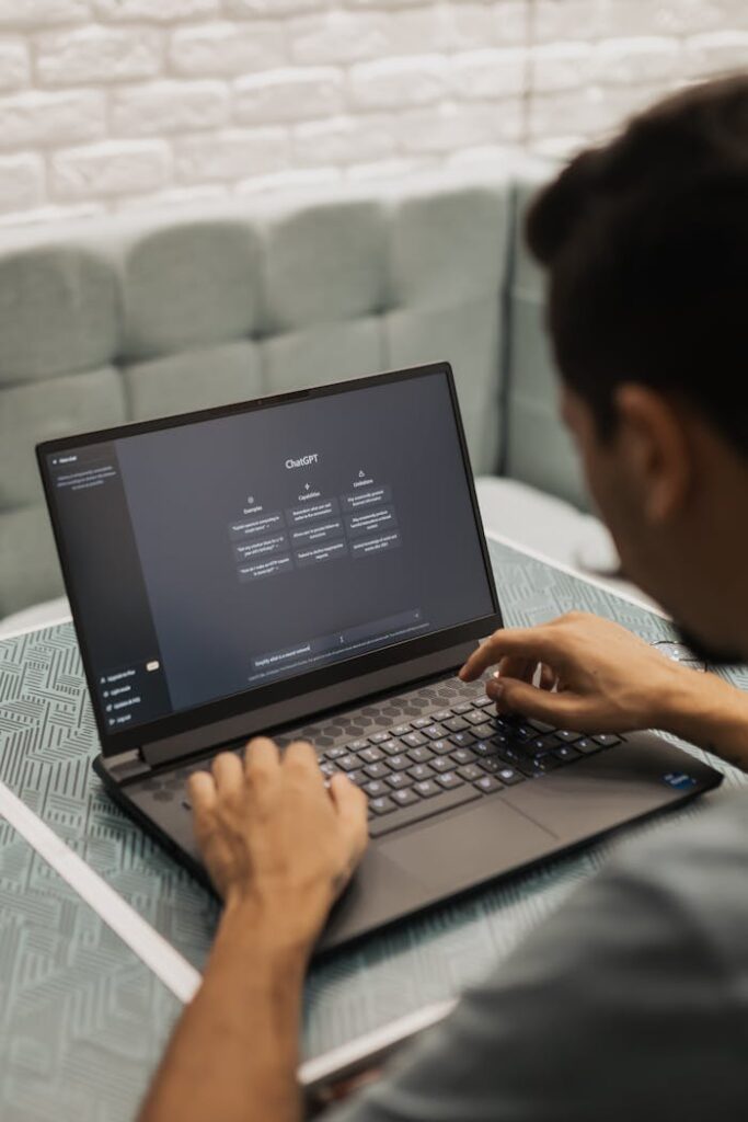 pexels-photo-16094038 A man types on a laptop running AI software, seated in a modern indoor setting.